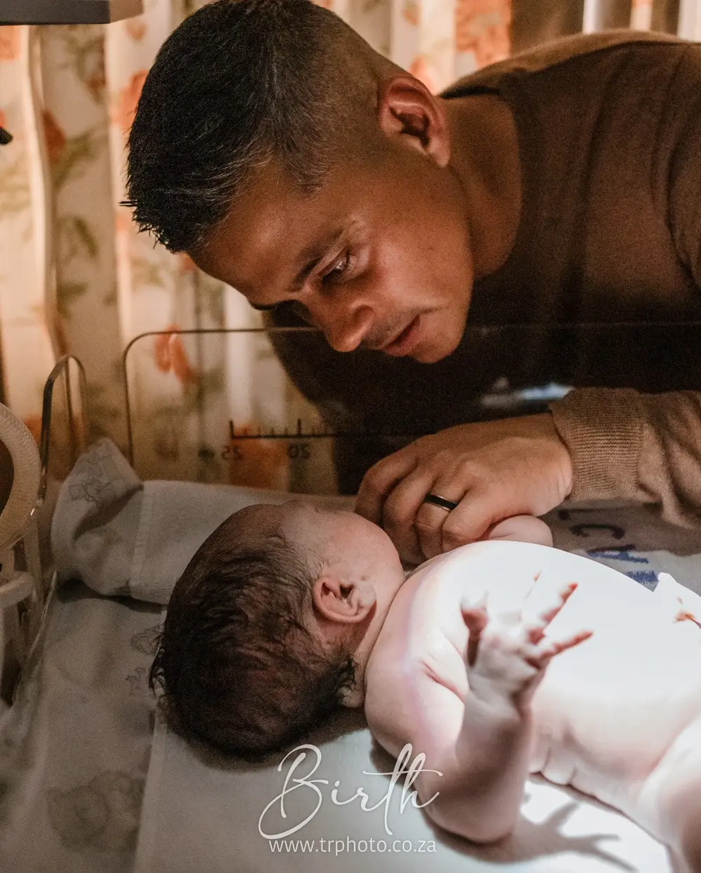 A father leaning over his newborn in hospital