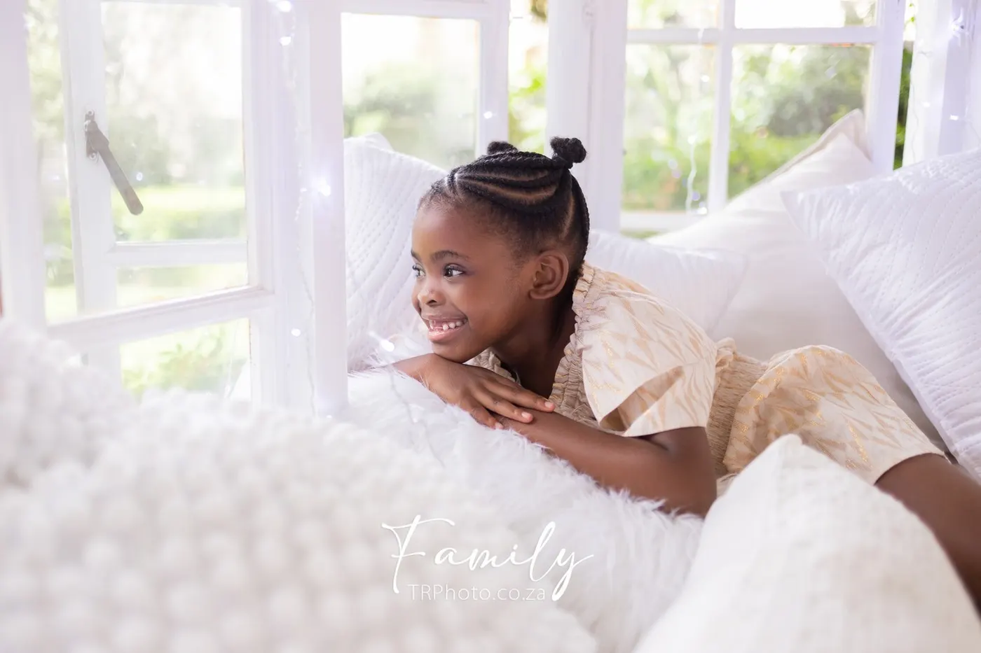 A smiling girl lying on white cushions