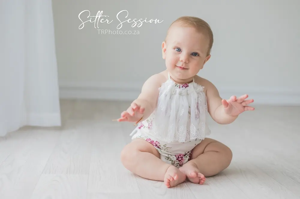 A baby sitting up and smiling