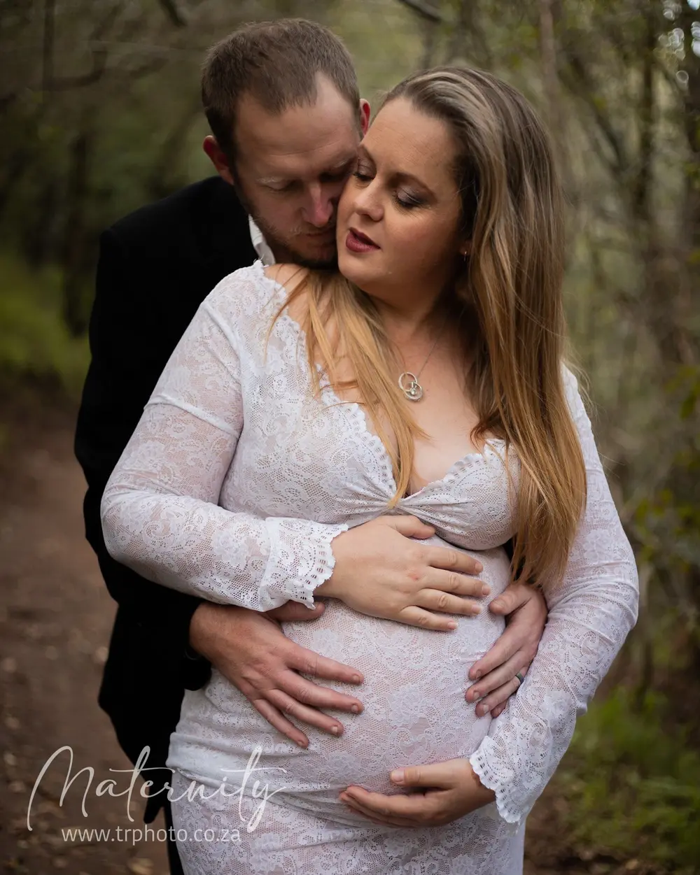 An expecting mother in a lace dress with her partner