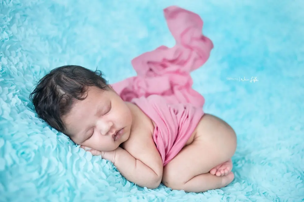 A newborn asleep on a blue blanket