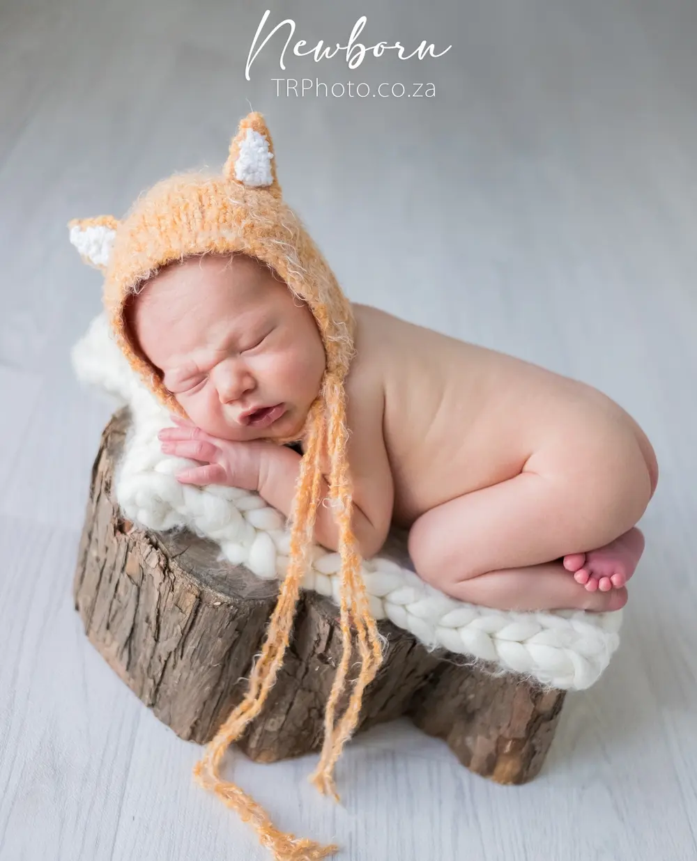 A newborn in a knitted fox bonnet