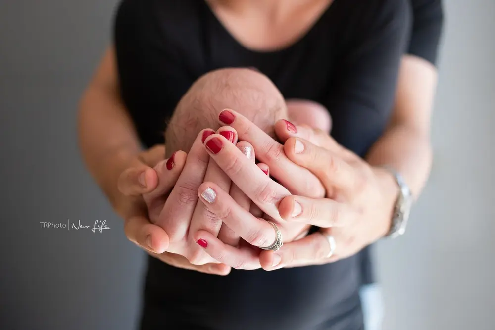 A parent's hands cradling a newborn