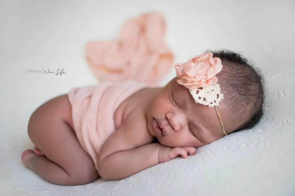 A sleeping newborn with a flower headband