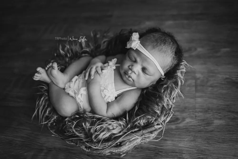 A newborn curled up in a woven nest